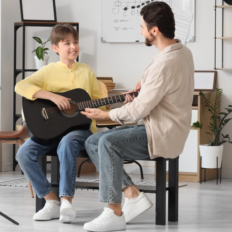 Gitarrenunterricht: Junge mit Gitarrenlehrer im Musikraum der Musikschule Fame